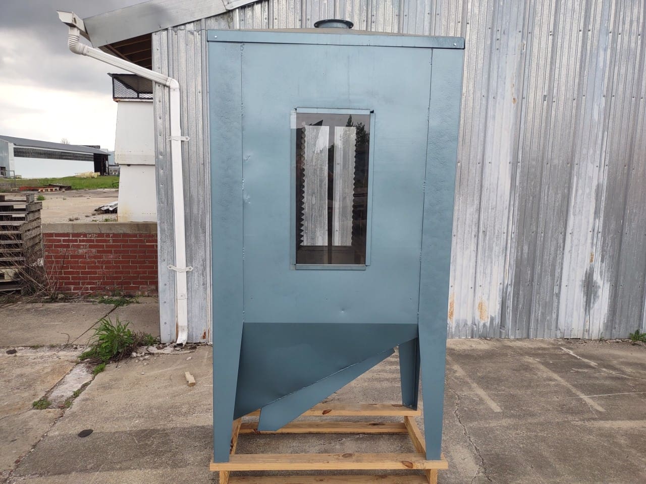 A blue machine sitting on top of a wooden pallet.