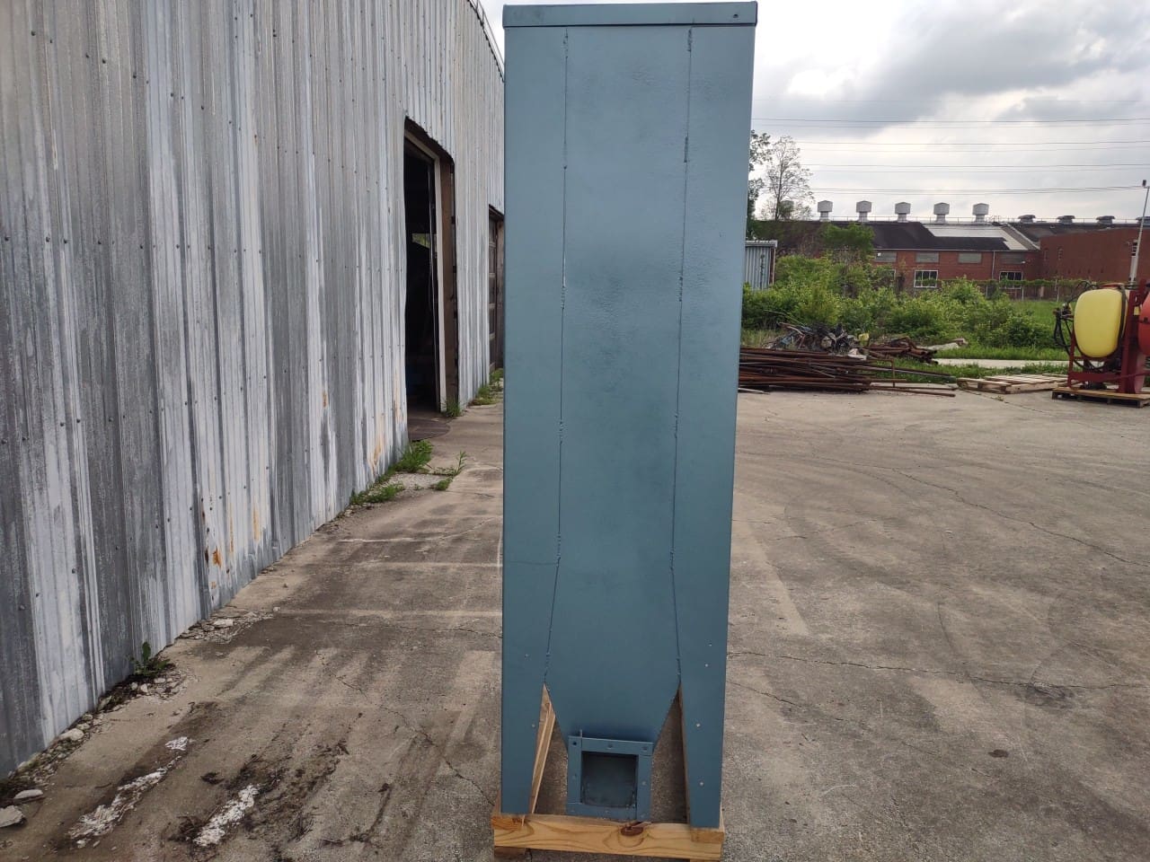 A blue cabinet is in the middle of an empty lot.