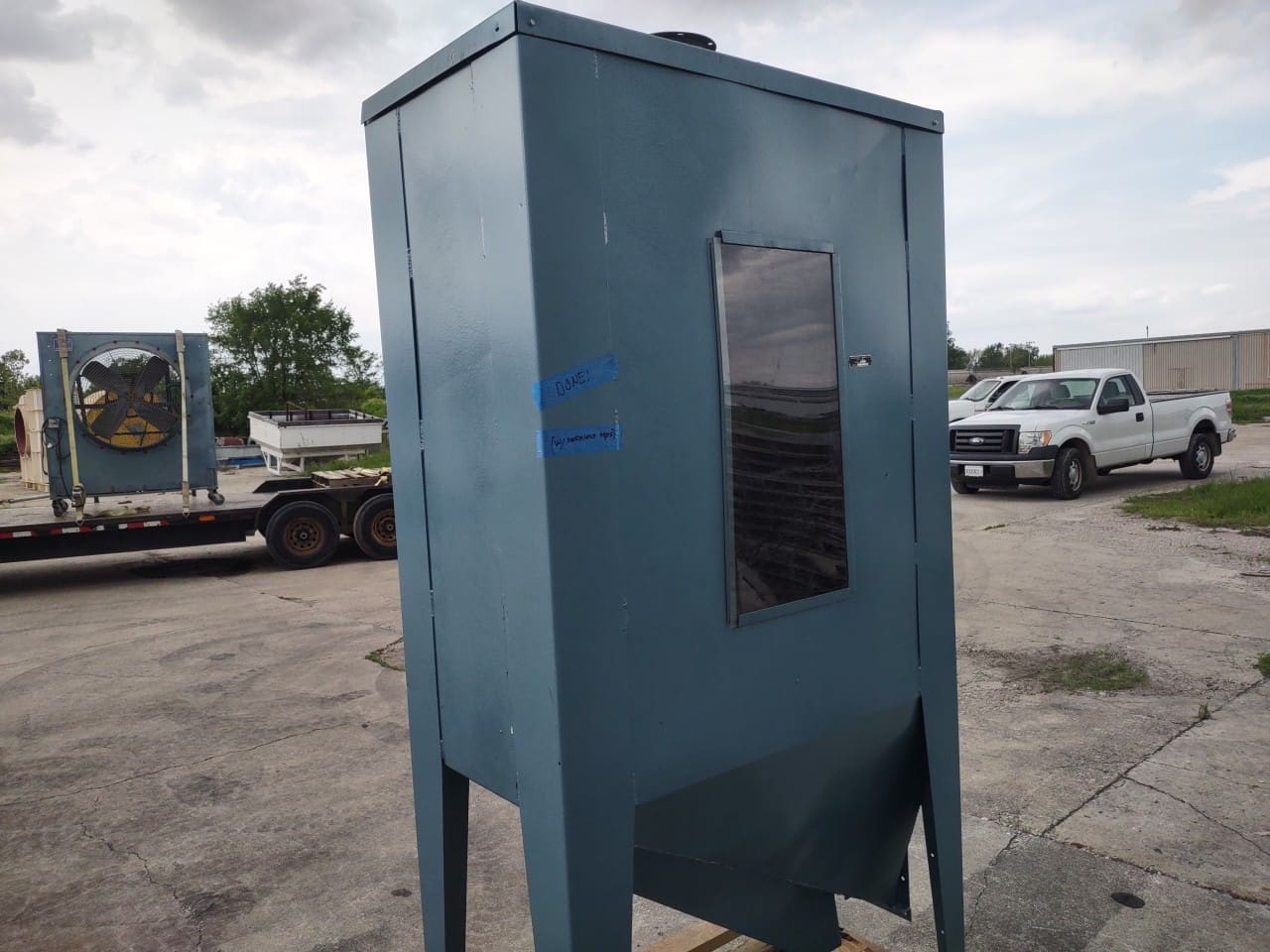 A blue metal box sitting in the middle of a parking lot.