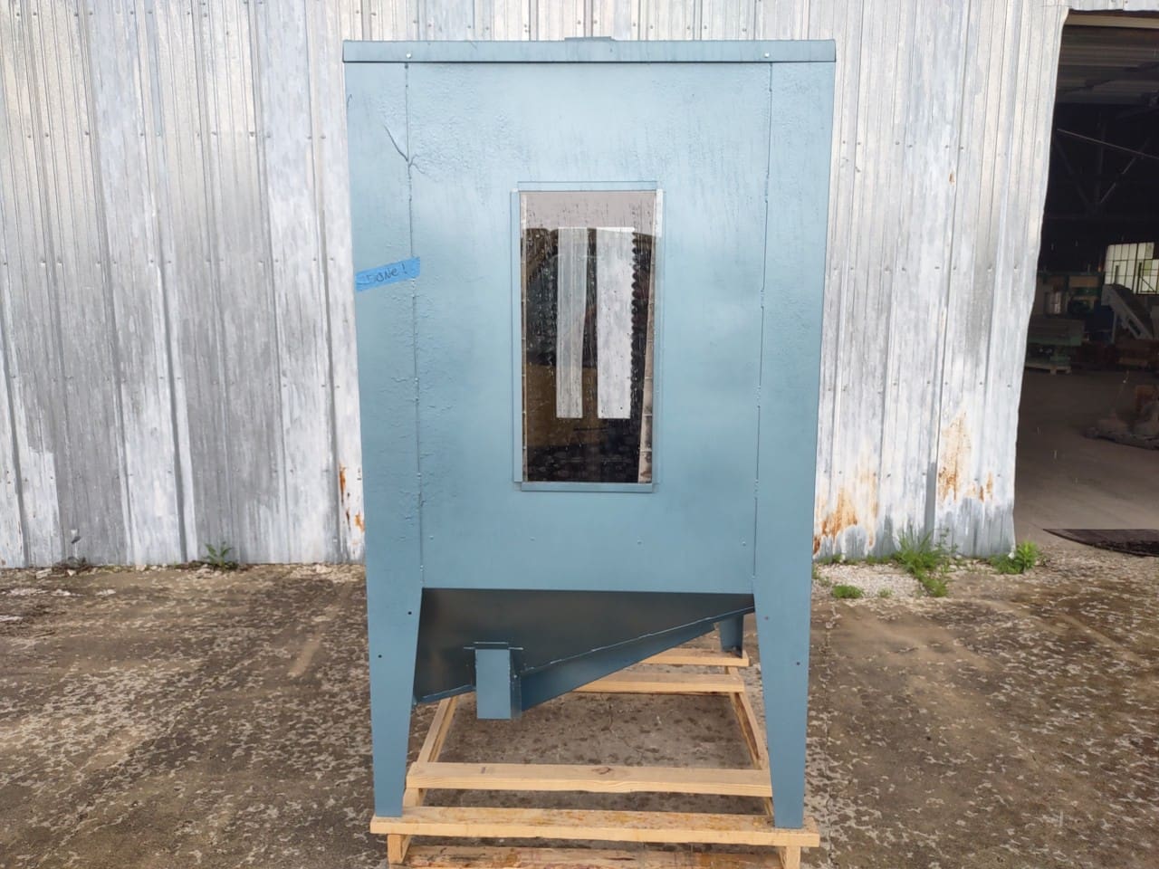 A blue machine sitting on top of a wooden pallet.