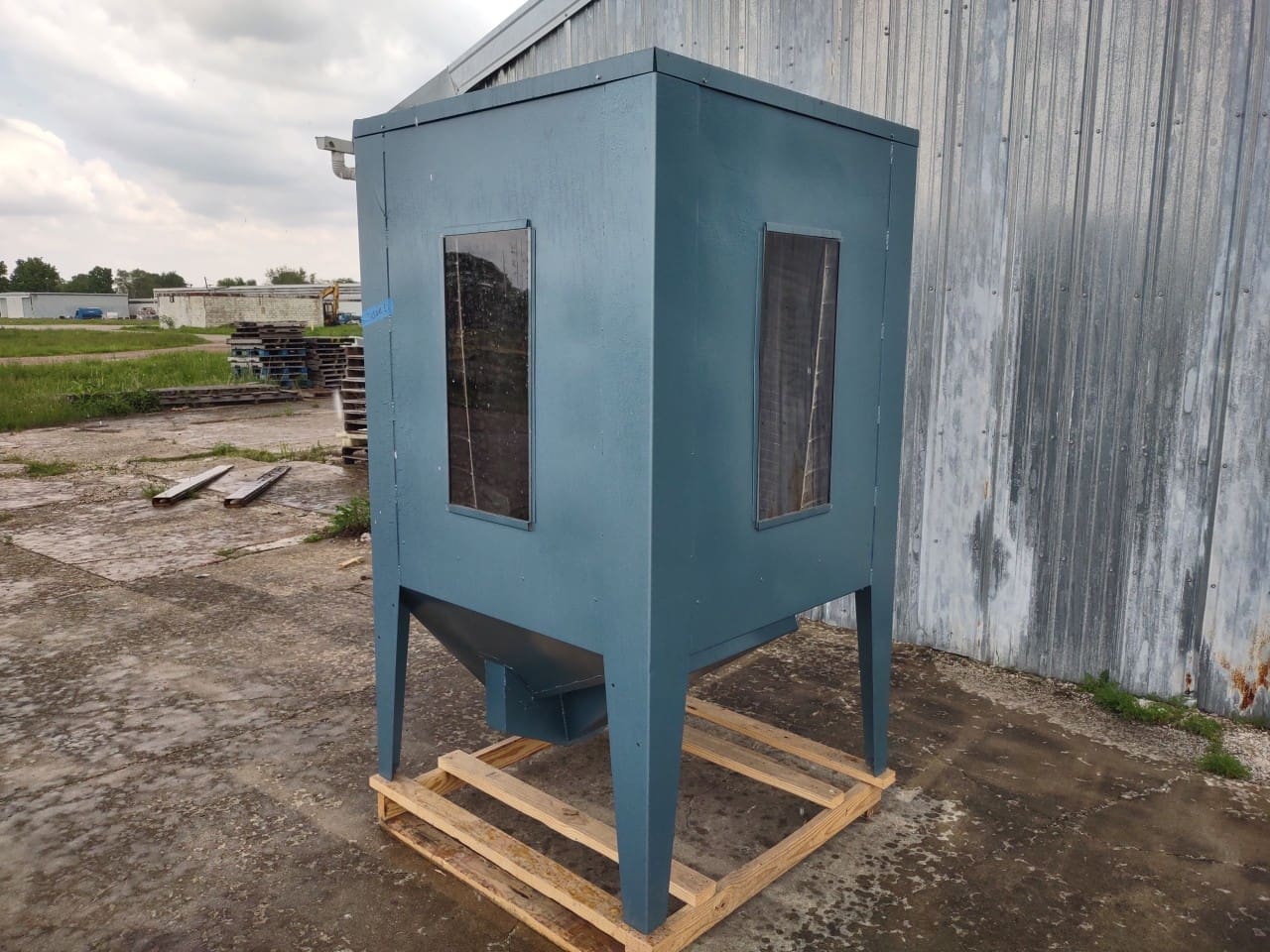 A blue metal box sitting on top of a wooden pallet.