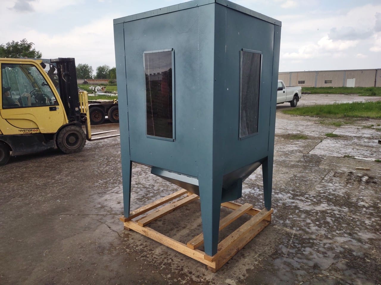 A blue metal box sitting on top of concrete.