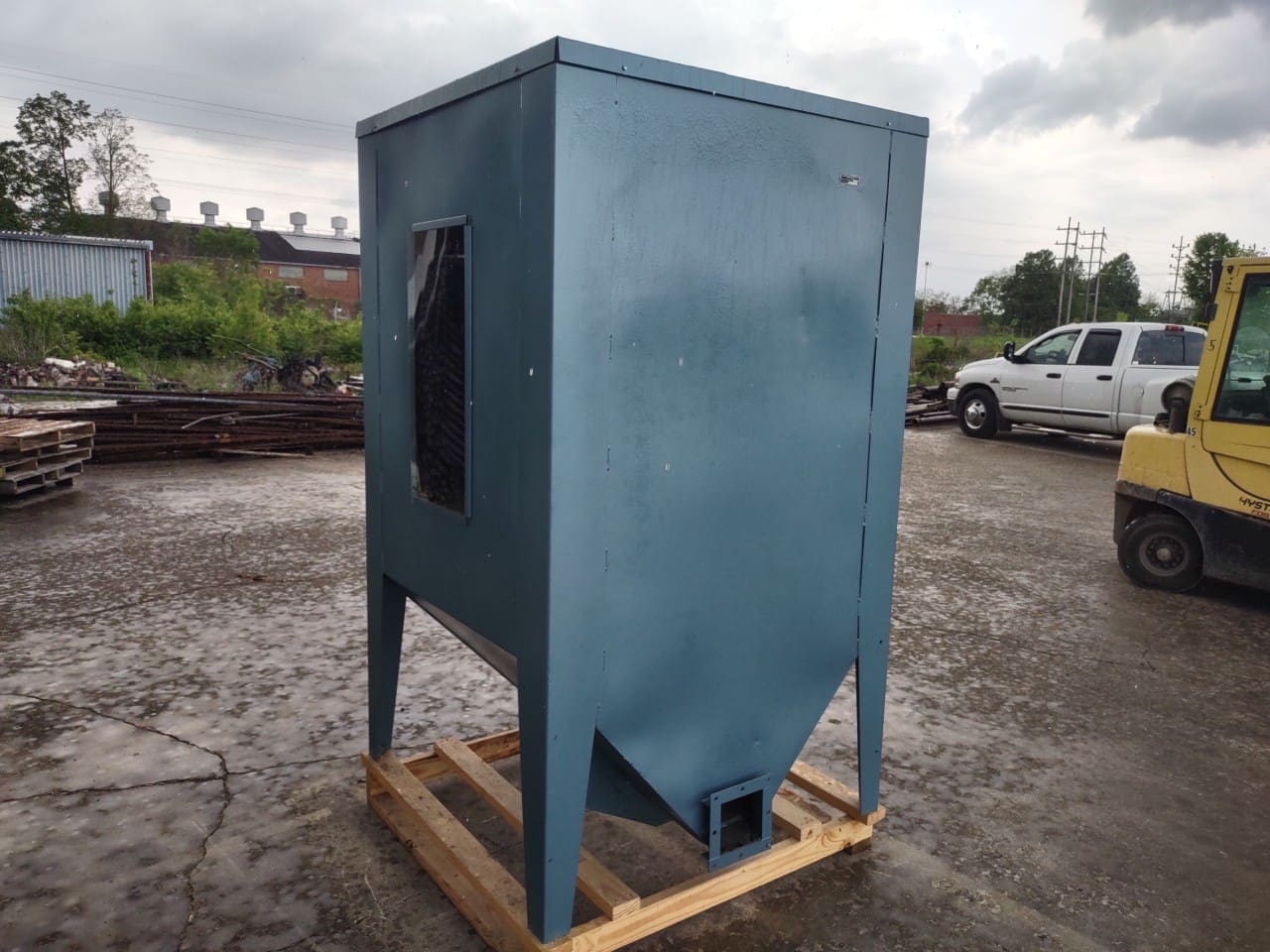 A blue machine sitting on top of a wooden pallet.