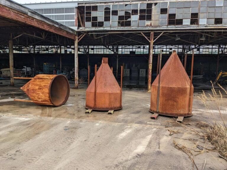 Three large rusted metal objects in a lot.