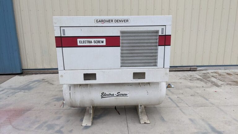 A white and red air compressor sitting on top of concrete.