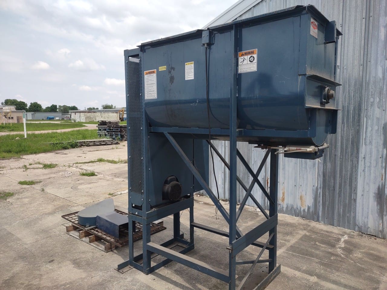 A large blue metal bin sitting on top of concrete.