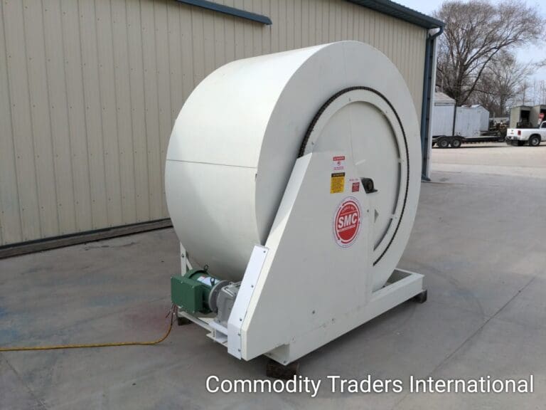 A white fan is sitting outside on the ground.