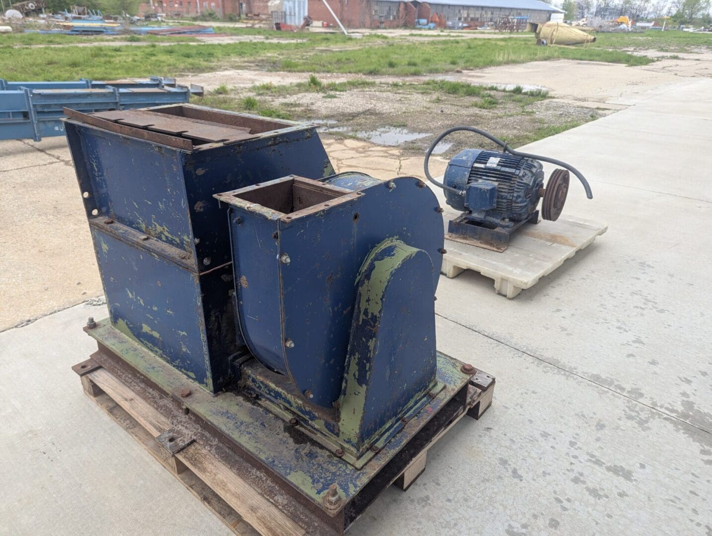 A blue machine sitting on top of a wooden pallet.
