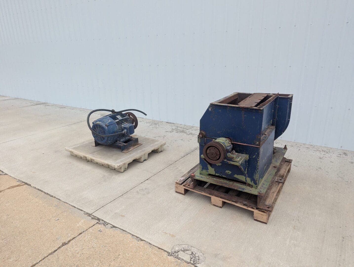 A blue machine and a small motor on top of some pallets.