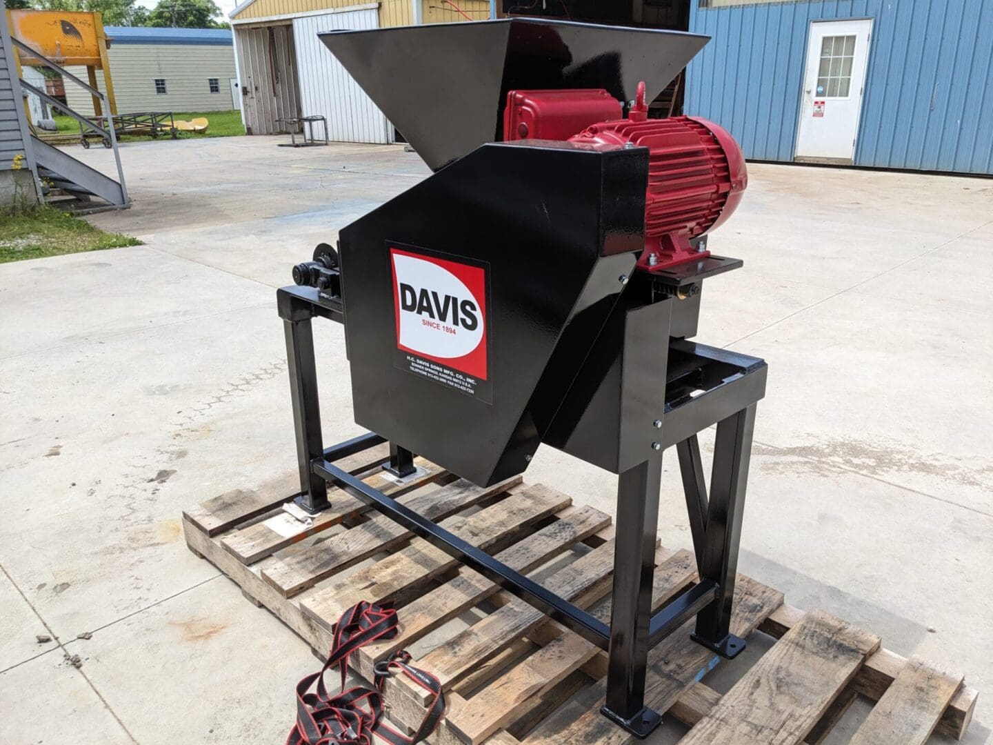 A red and black machine on top of a wooden pallet.