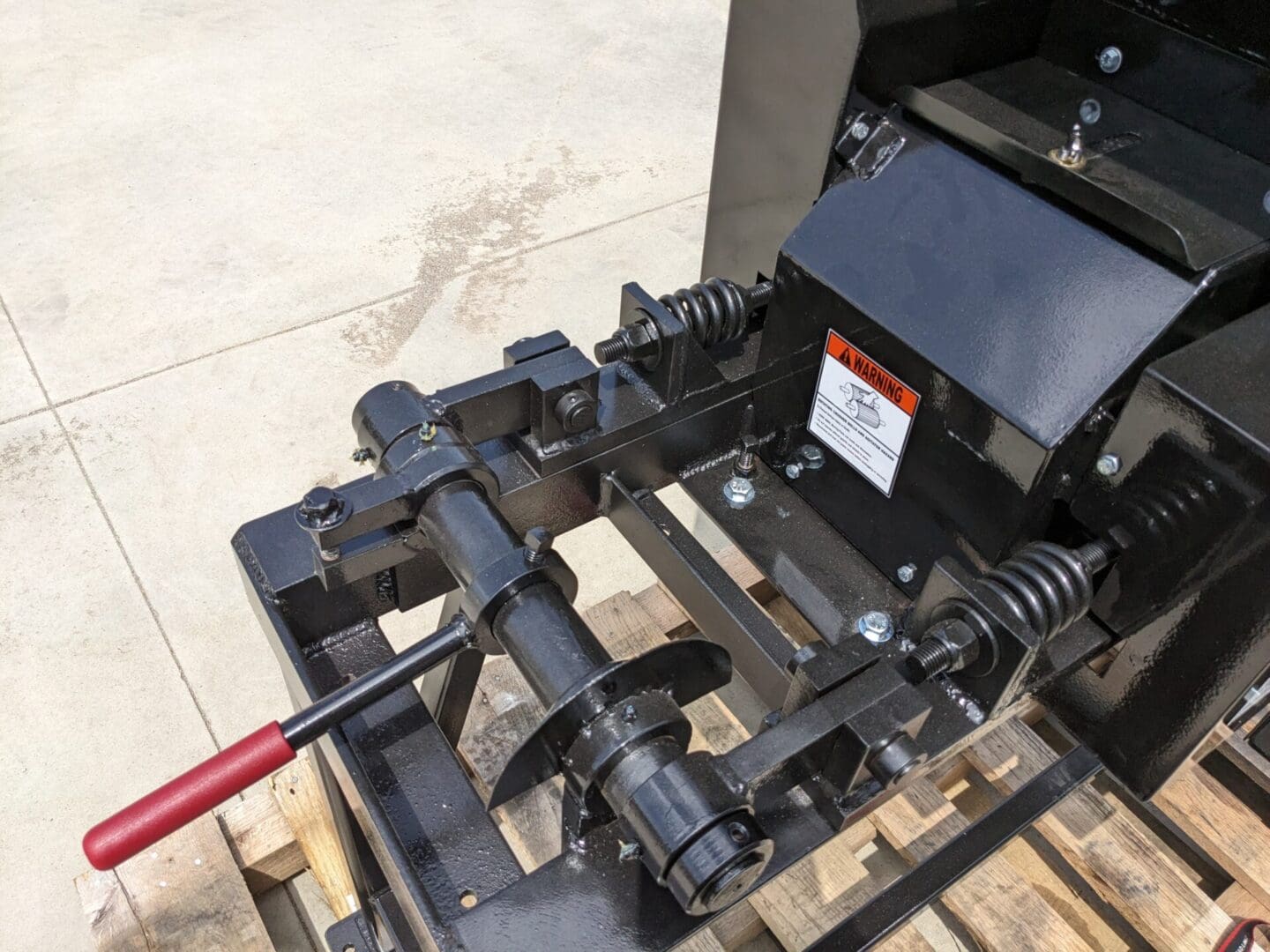 A red stick is attached to the front of a machine.