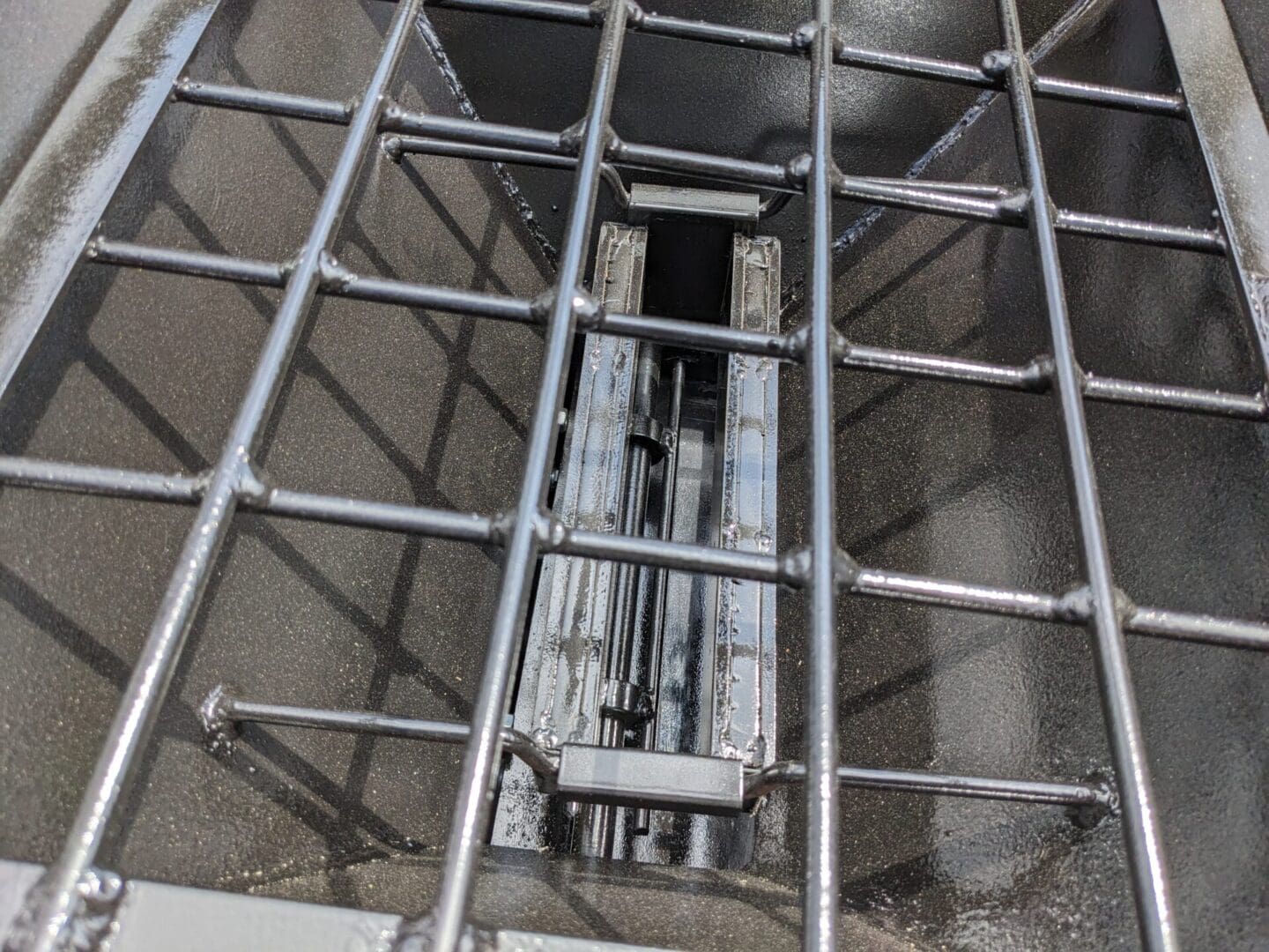 A metal cage with a door open and some pipes