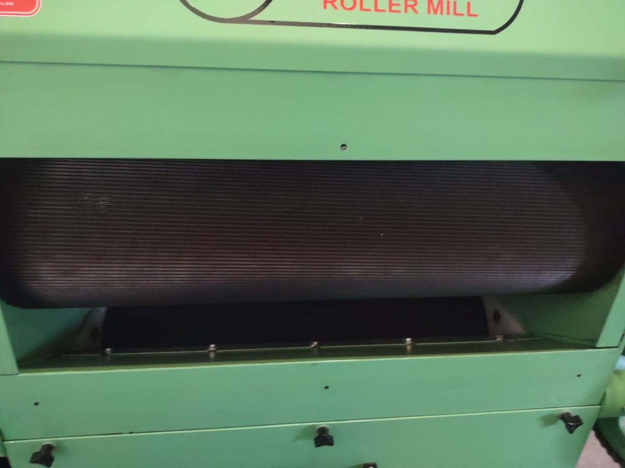 A roller mill is shown with the belt in front of it.
