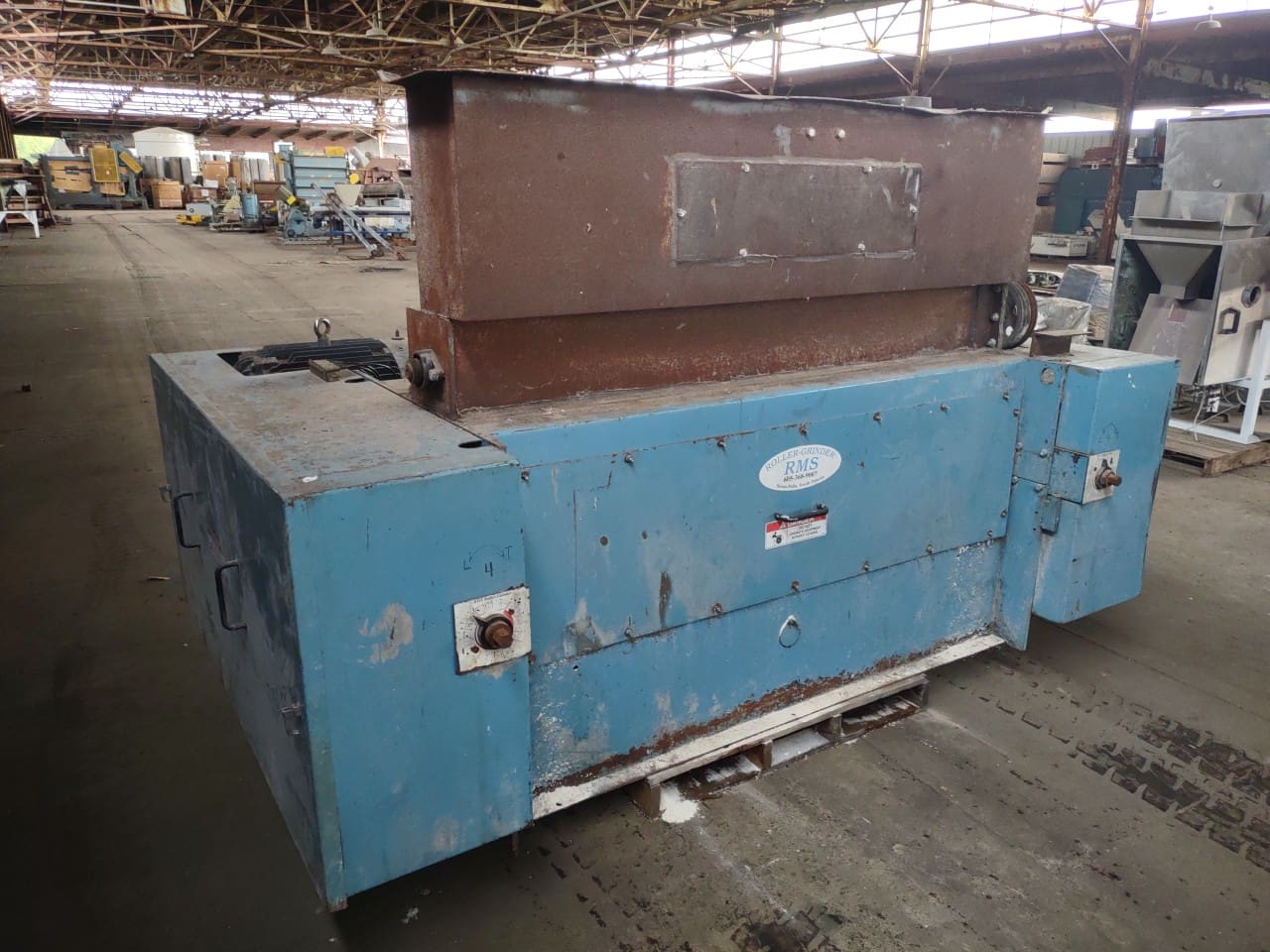 A large blue machine in an old warehouse.