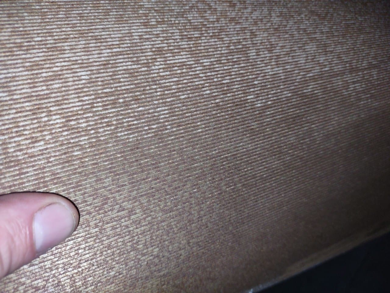 A person is touching the fabric of a couch.