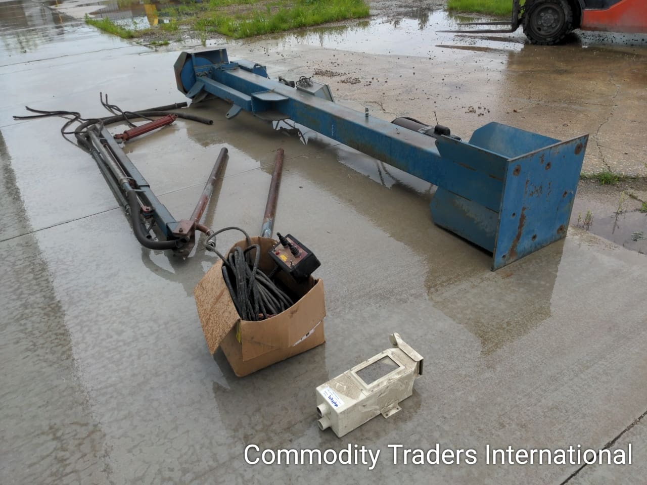 A box of junk sitting on the ground in front of a crane.
