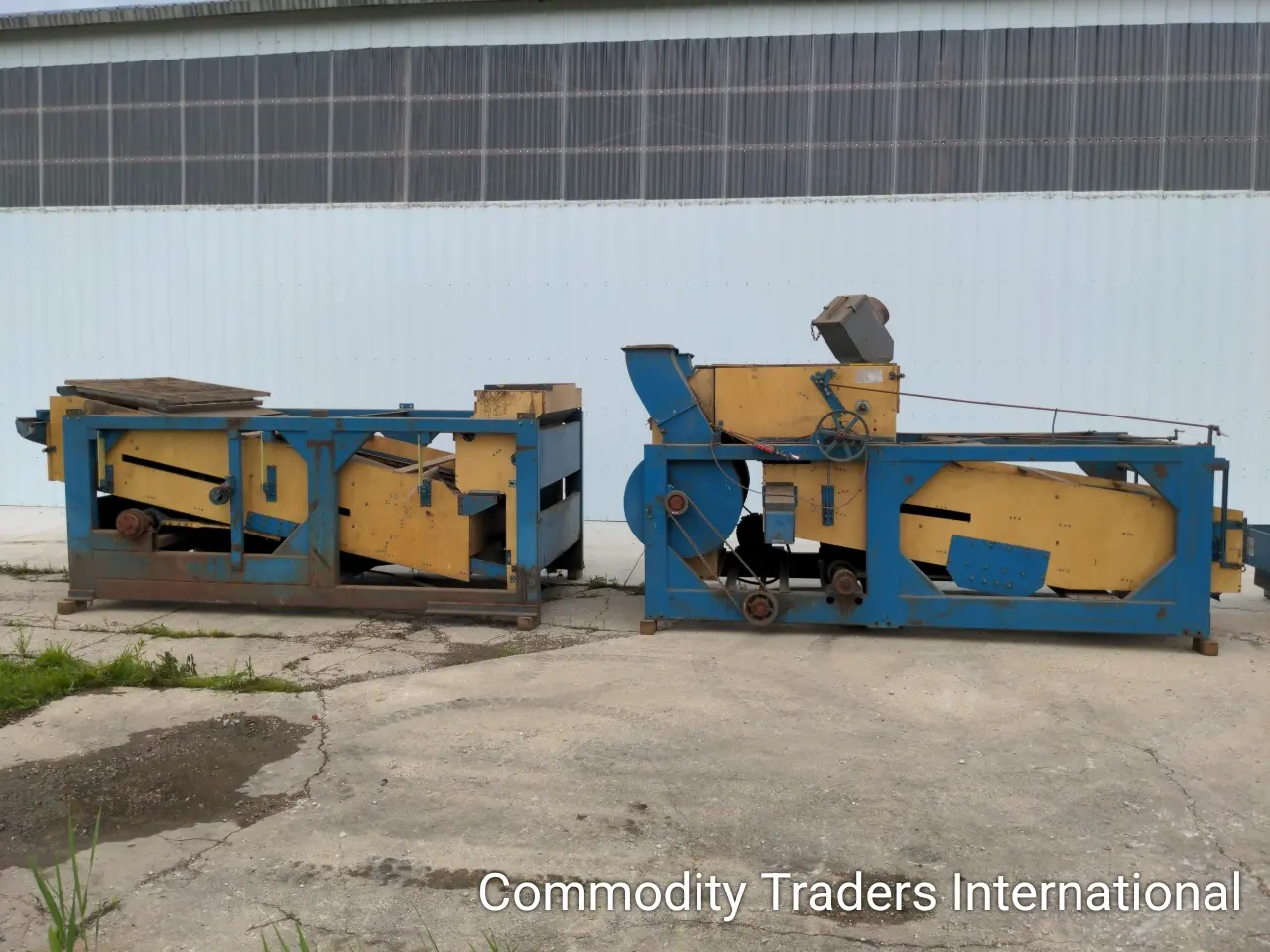 A couple of blue and yellow machinery sitting in the middle of a lot.