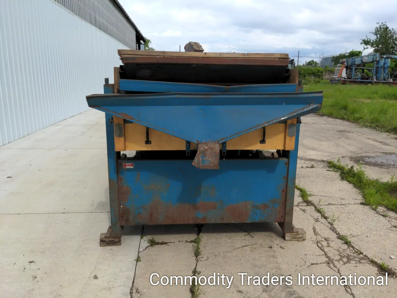 A blue and yellow dumpster on the side of a road.