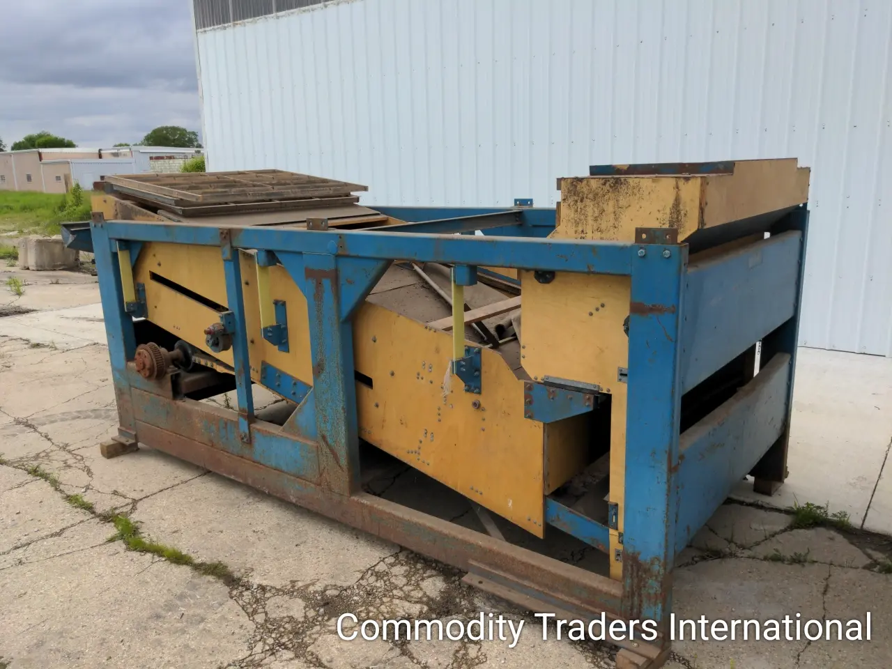 A blue and yellow dumpster sitting on the side of a road.