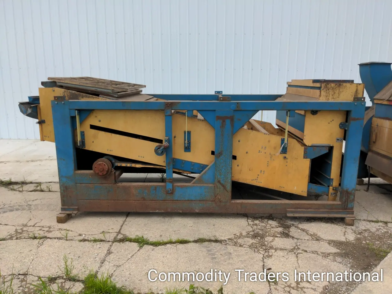 A blue and yellow dumpster sitting on the side of a road.