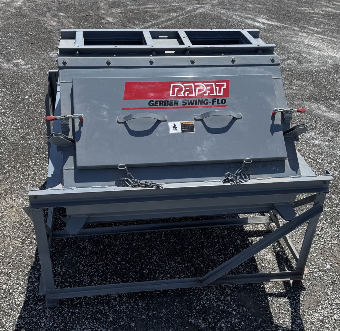 A large metal box sitting on top of a gravel ground.