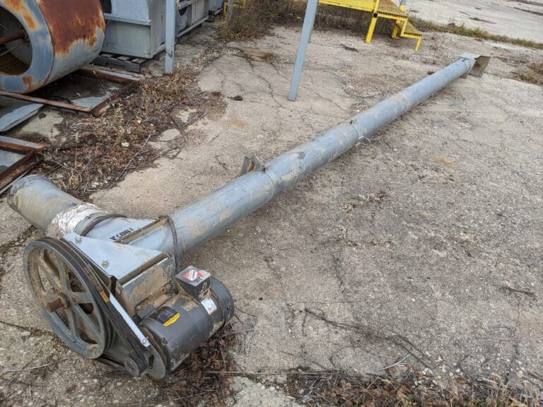 A pipe laying on the ground next to a building.
