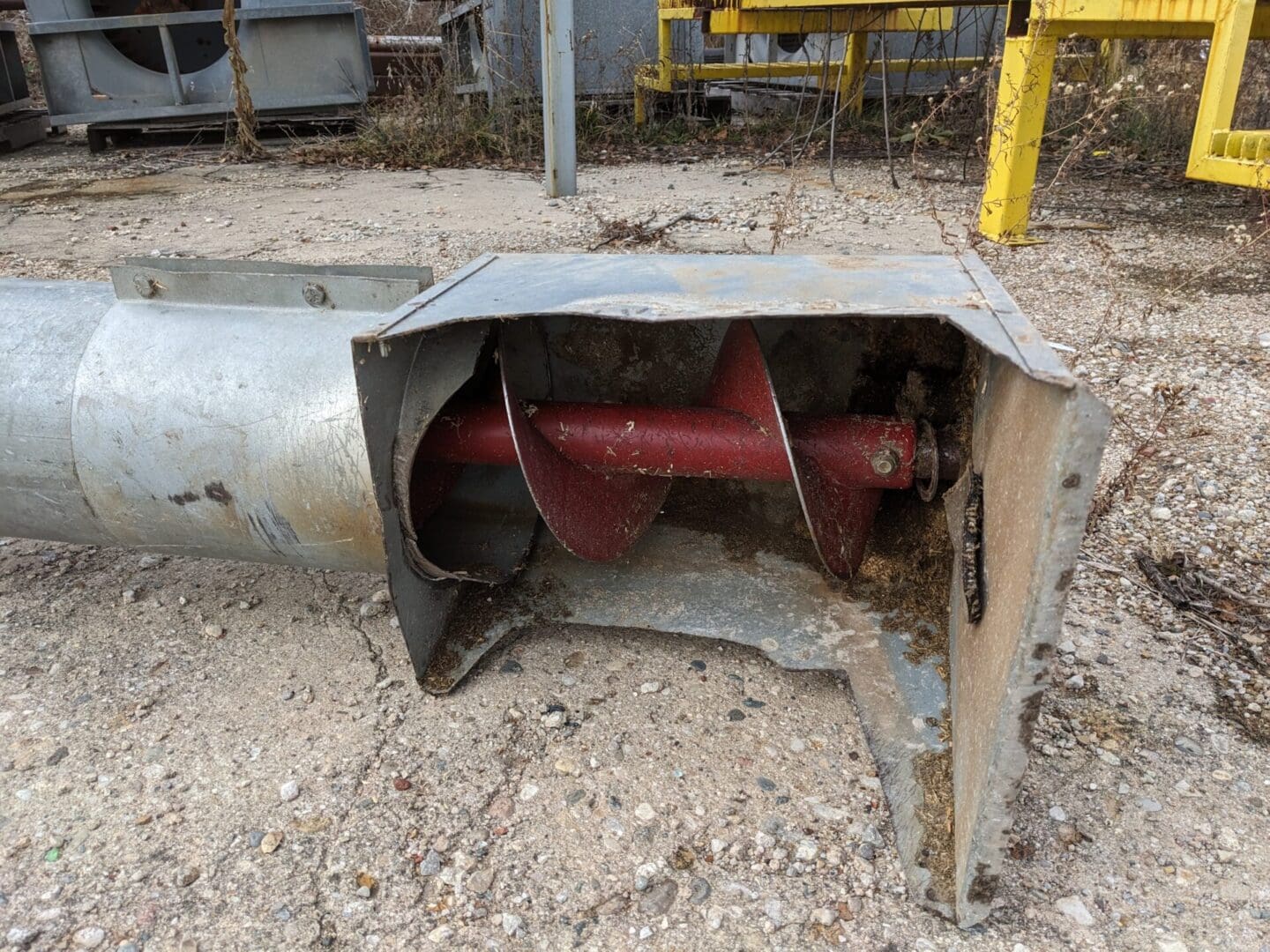 A rusted metal pipe with a red and yellow piece of machinery in it.