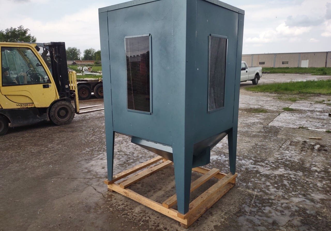 A blue metal box sitting on top of concrete.
