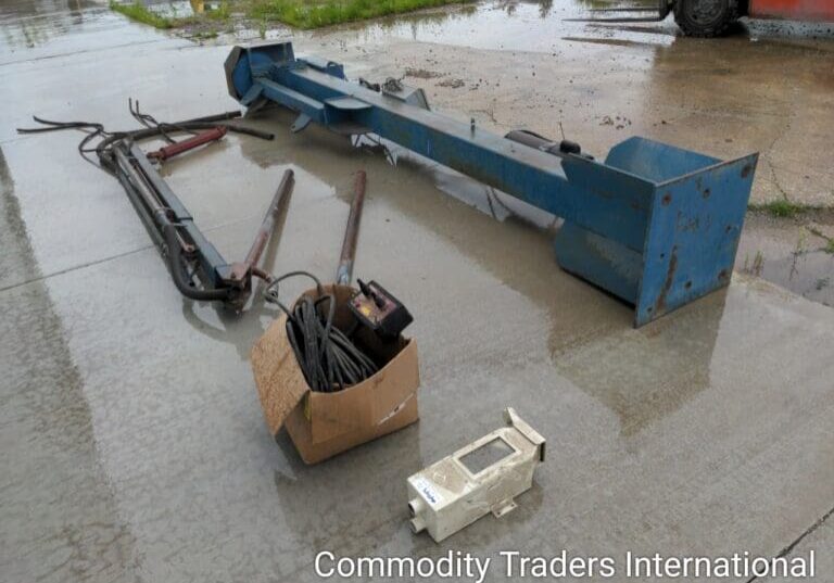 A box of junk sitting on the ground in front of a crane.