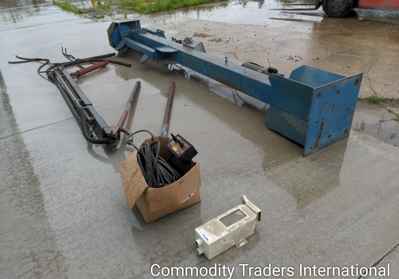 A box of junk sitting on the ground in front of a crane.