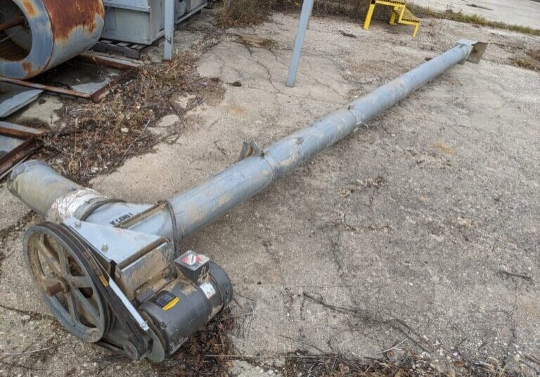 A pipe laying on the ground next to a building.