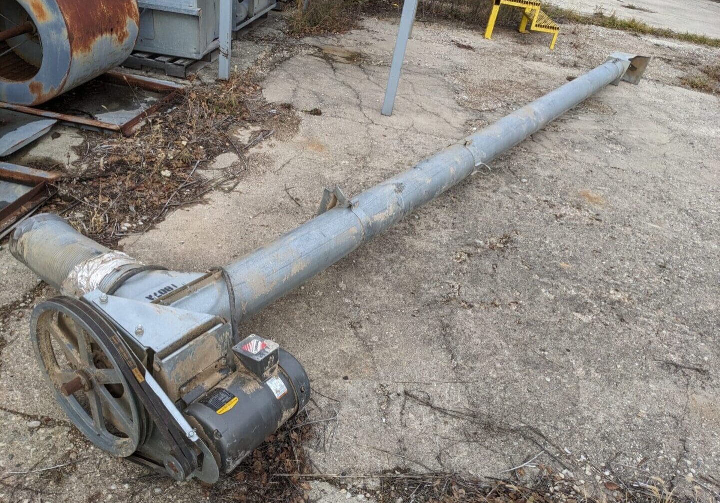 A pipe laying on the ground next to a building.